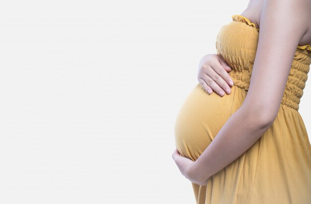 A pregnant woman gently holding her baby bump.
