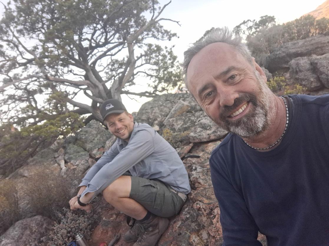 Two men sitting on rocks and smiling

Description automatically generated