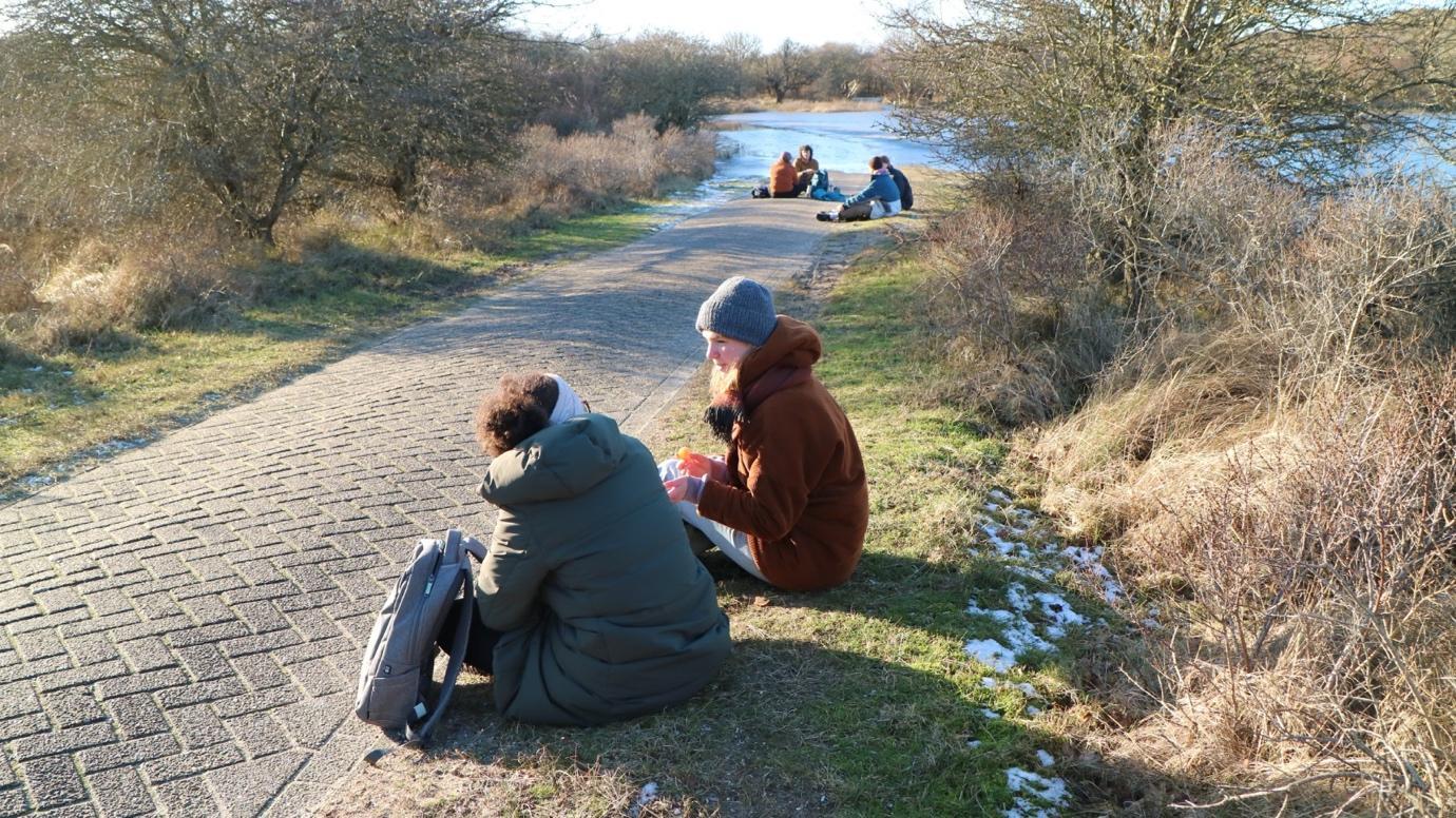 A group of people sitting on a path

Description automatically generated