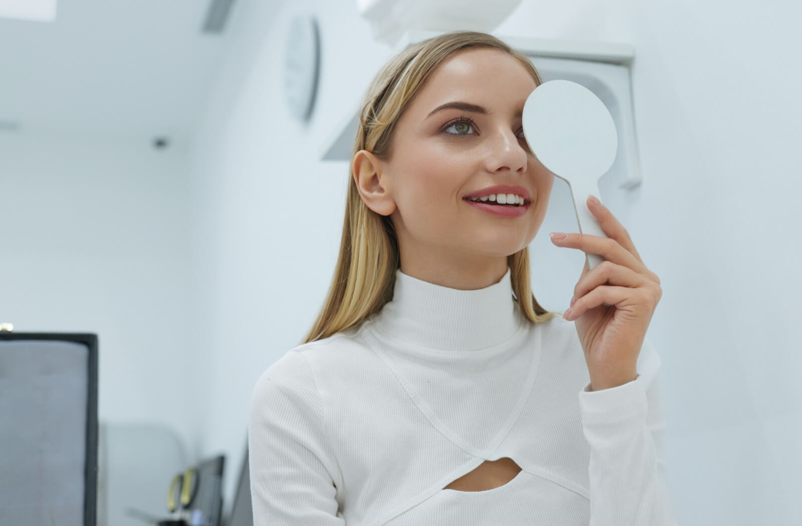 A person with a white occluder blocking their left eye undergoing a visual acuity test
