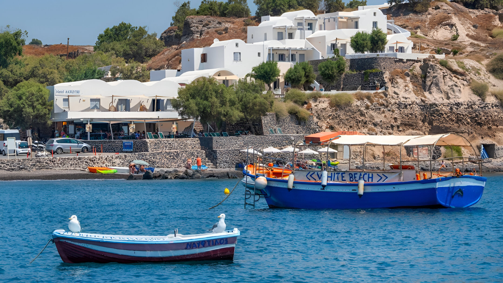 Boats on the waters with white-washed buildings in the background in Santorini