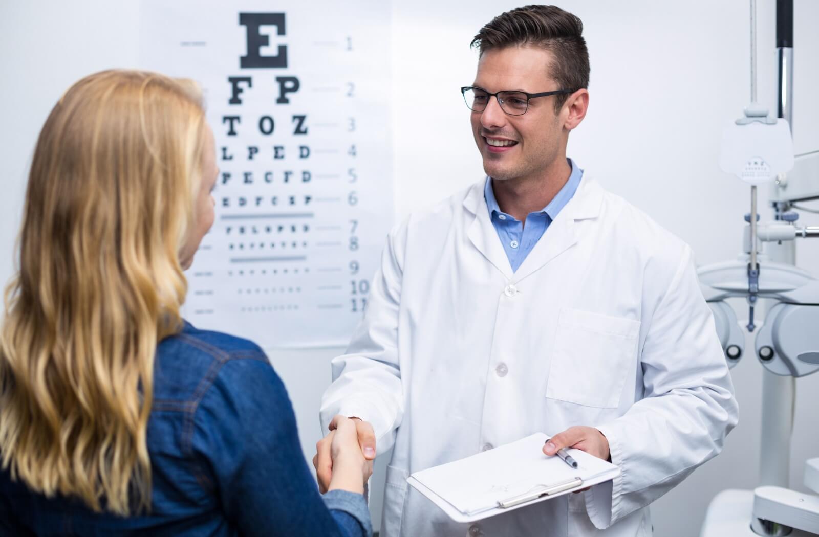 A woman in an optometry clinic shaking hands with her male optometrist
