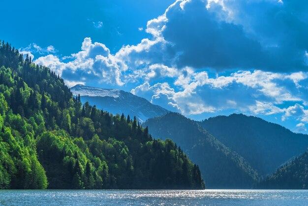Free photo beautiful lake ritsa in the caucasus mountains. green mountain hills, blue sky with clouds. spring landscape.