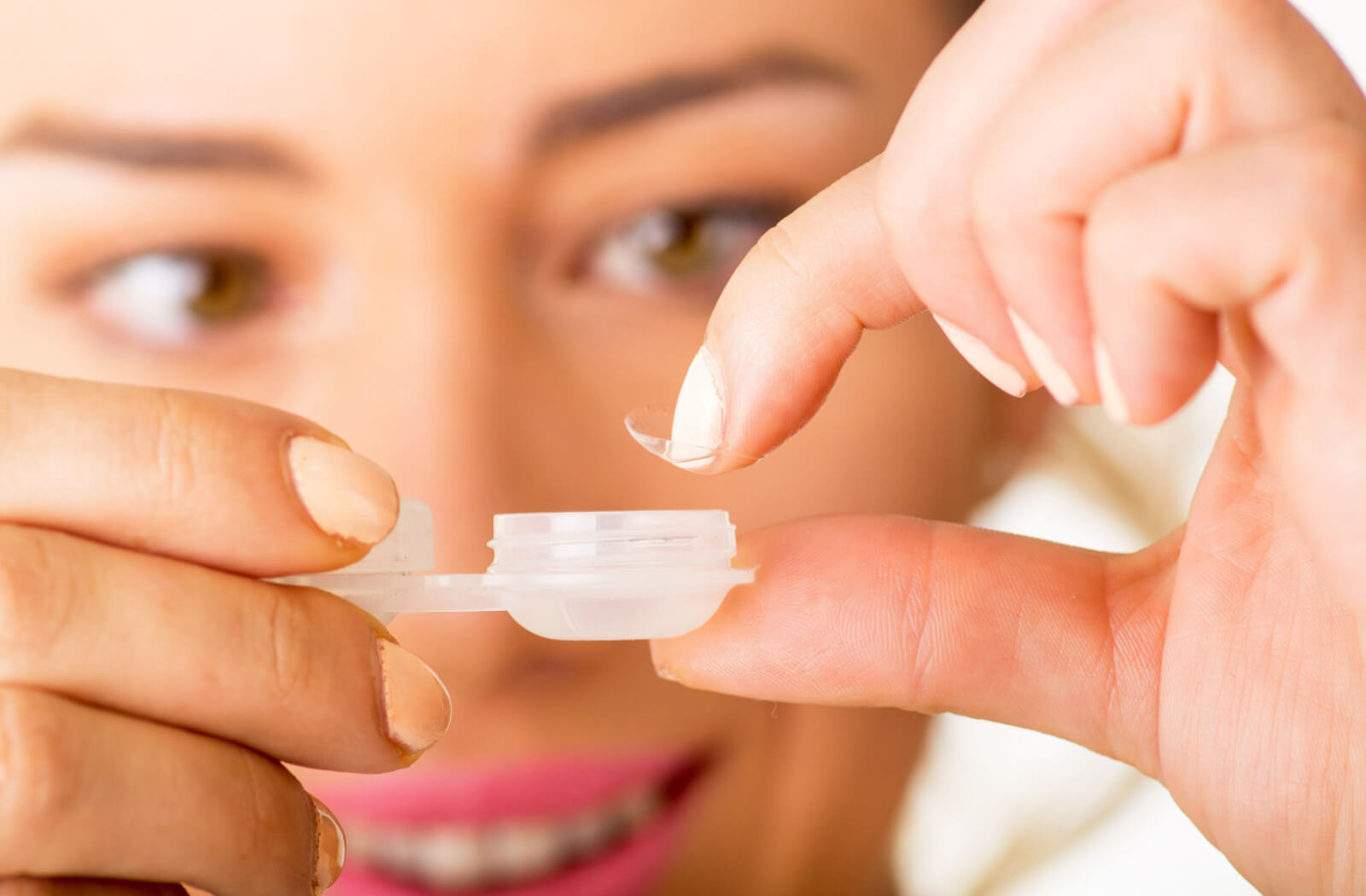 A woman storing her contact lens in a plastic contact lens container.