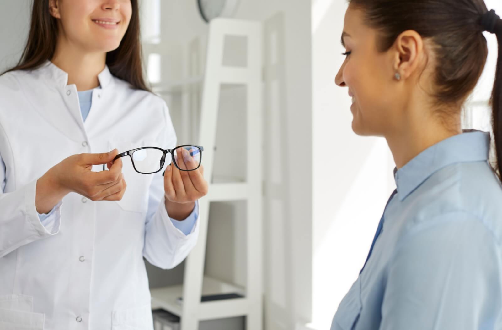 An optometrist presenting a pair of eyeglasses to her patient.