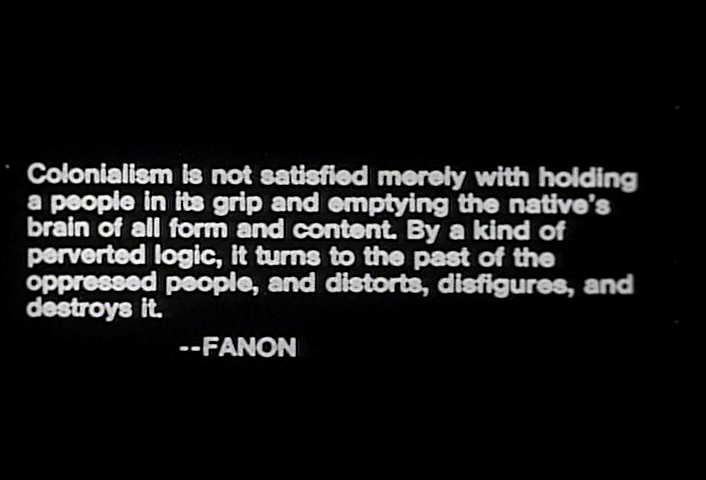 Black background with white text: Colonialism is not satisfied merely with holding a people in its grip and emptying the native's brain of all form and content. By a kind of perverted logic, it turns to the past of the oppressed people, and distorts, disfigures, and destroys it. -- FANON