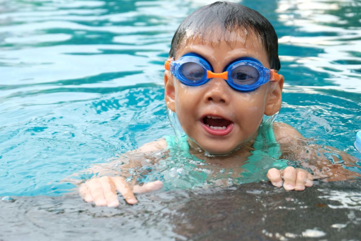 a toddler swimming wearing blue goggles