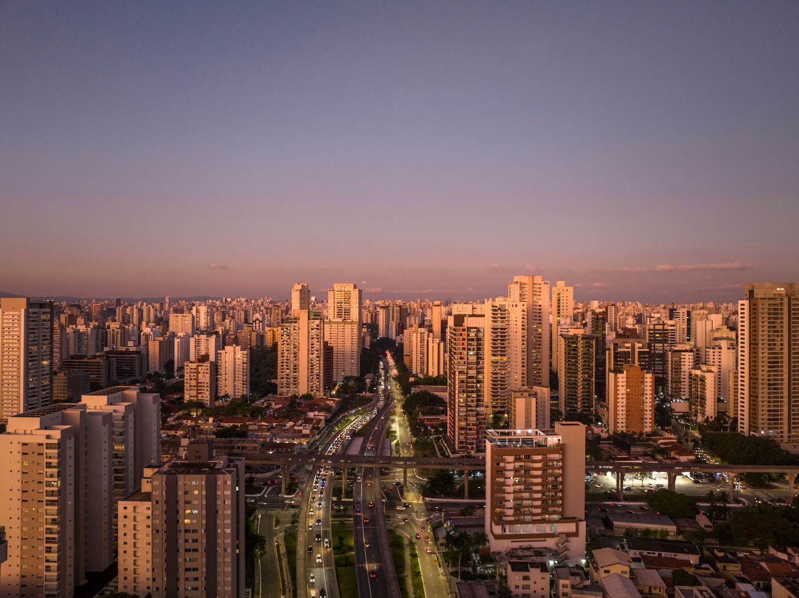 Foto da cidade de São Paulo ao entardecer com vários prédios ao fundo.