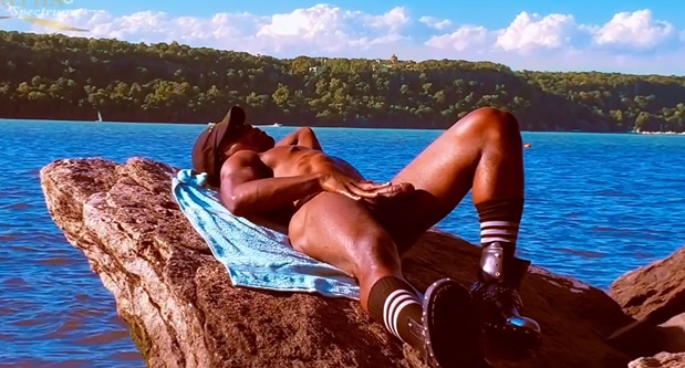 Jordan Jameson lying naked on a rock near the ocean stroking his hard cock