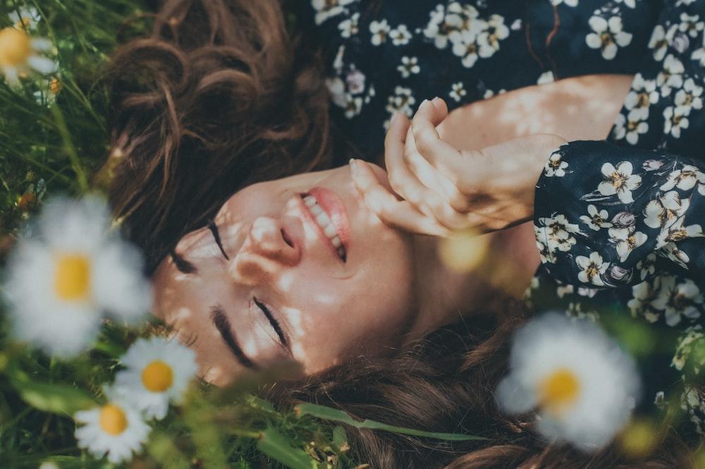 woman in black and white floral shirt lying on green grass field