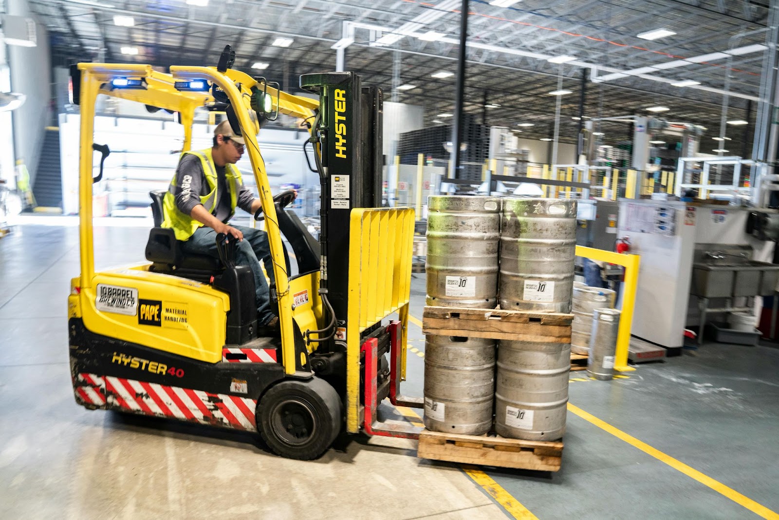 A yellow forklift hauling metal cans