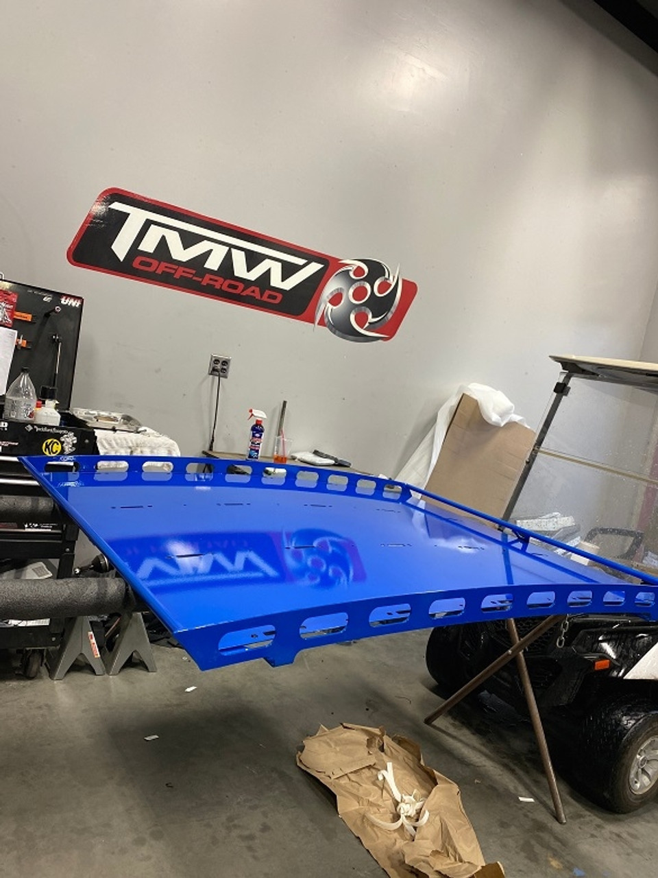 A blue Can-Am Maverick X3 roof rack, displayed in a workshop