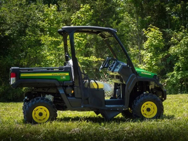 A side-facing image of a John Deere UTV, uninhabited and parked on grass, and lifted by a John Deere Gator XUV 2" Lift Kit