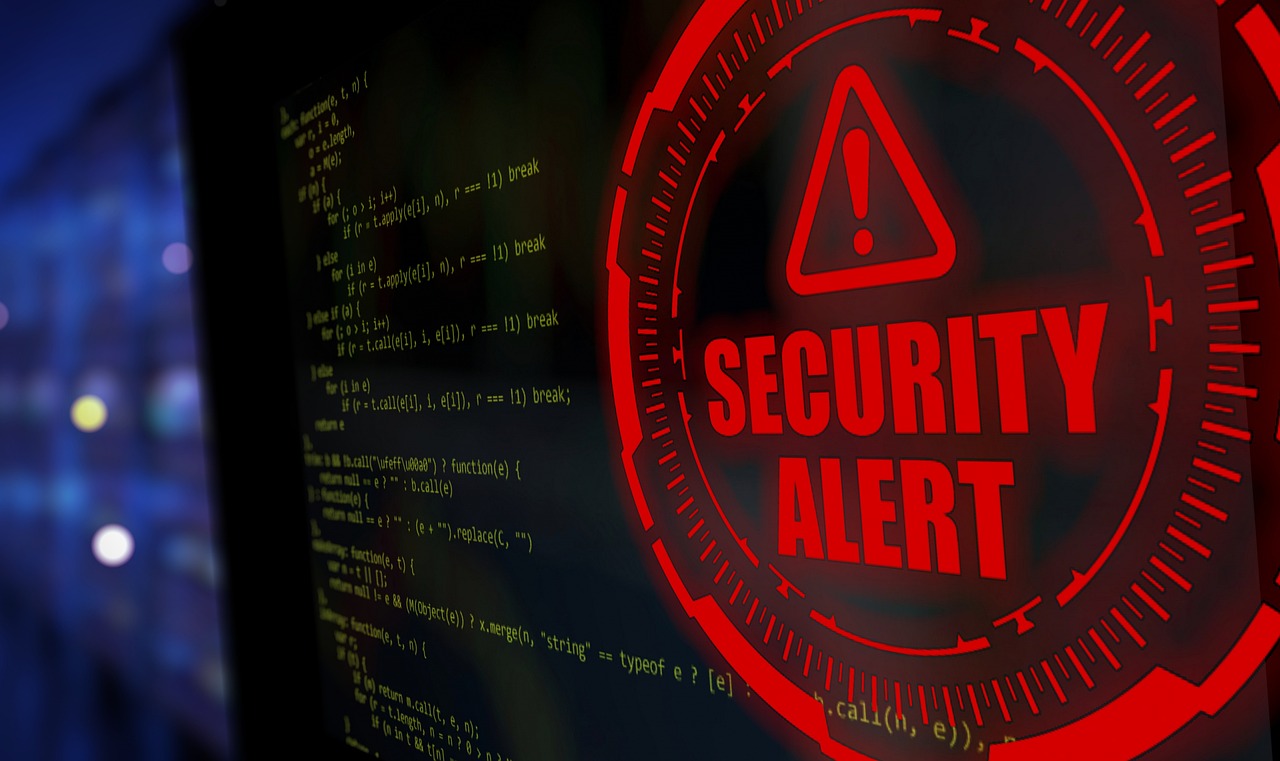 A computer screen displaying a prominent, glowing red "SECURITY ALERT" symbol indicating a cyber security threat or breach.