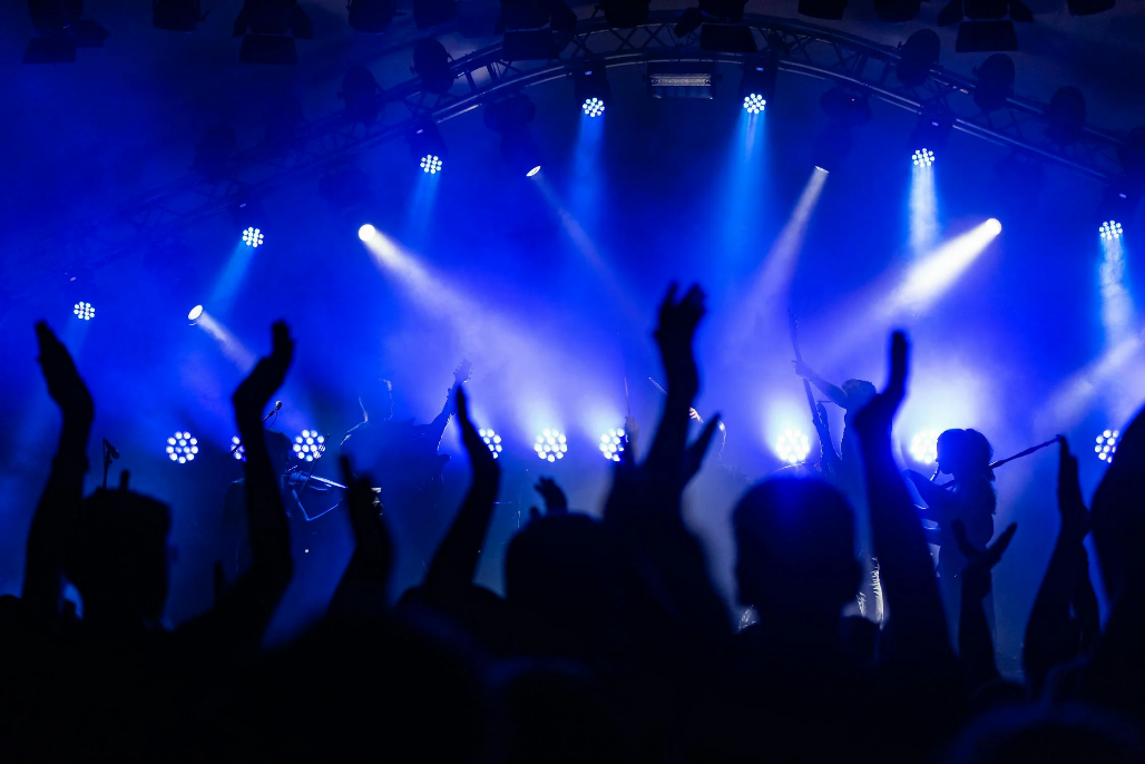 A crowd of people on a stage with bright lights

Description automatically generated