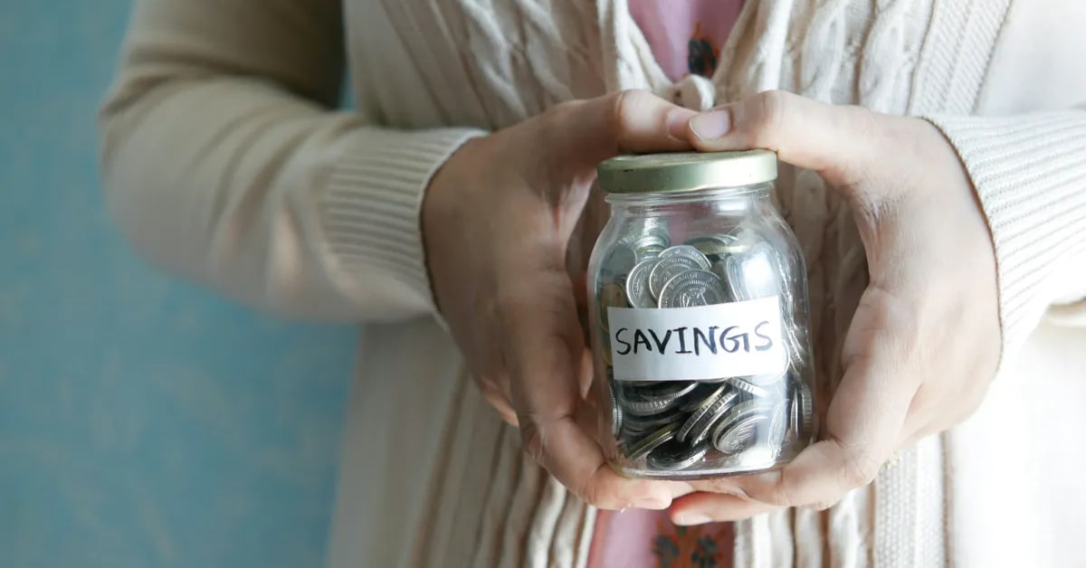 Woman holding a glass jar filled with coins