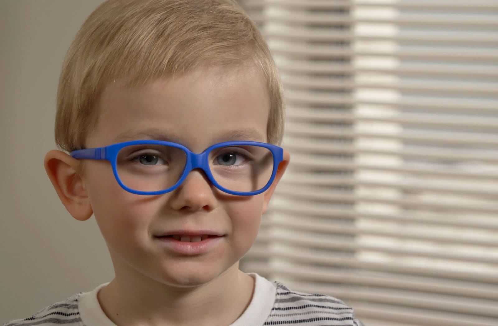 A close-up of a young boy wearing blue-framed myopia control eyeglasses.