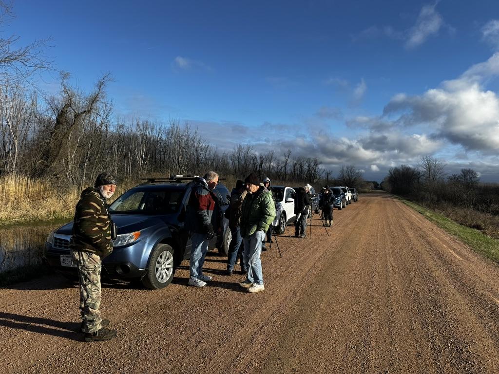 A group of people standing on a dirt road

Description automatically generated