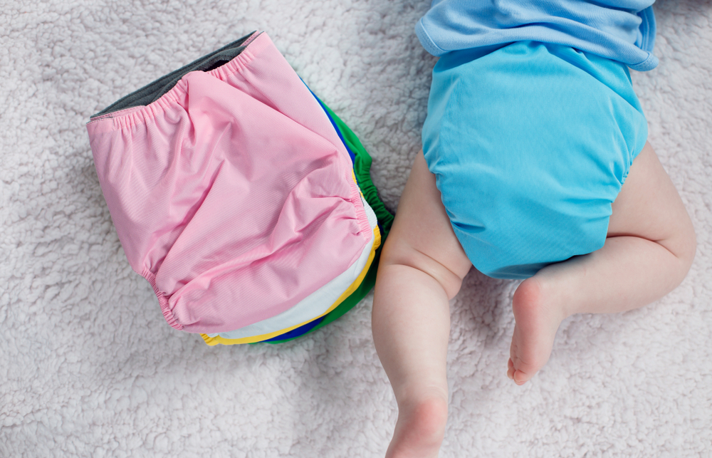 baby lying next to the stack of cloth diaper 