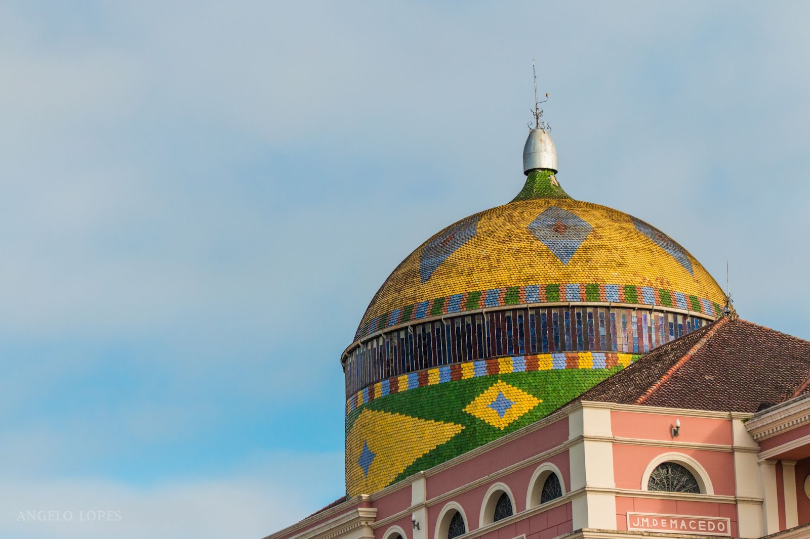 Cúpula do Teatro Amazonas. A estrutura redonda é adornada por ladrilhos cerâmicos em cores vibrantes, como amarelo, azul e verde. O formato do mosaico lembra a bandeira do Brasil.