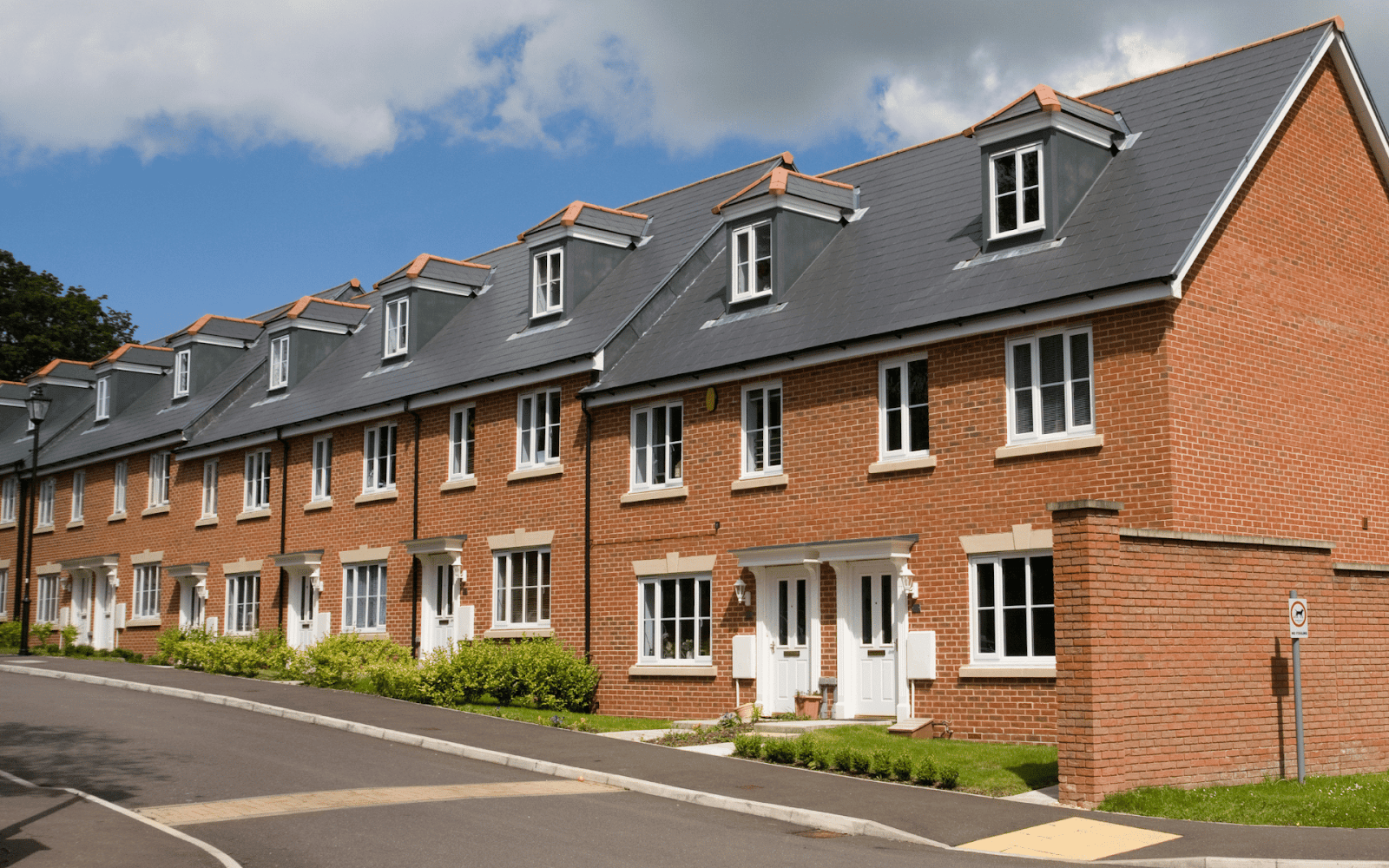 A row of brick buildings with a street and blue skyDescription automatically generated