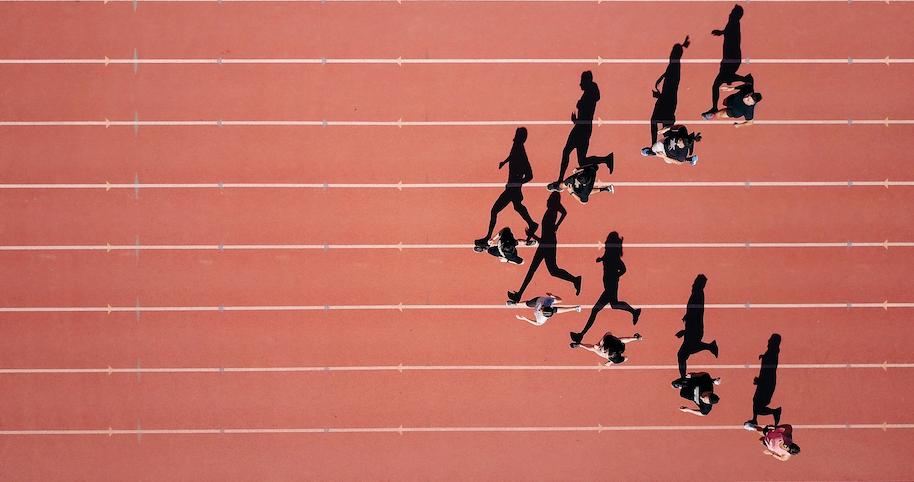 An aerial view of eight people running in the track field.