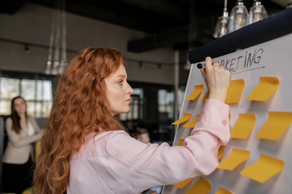 Woman Writing on a Whiteboard with Sticky Notes