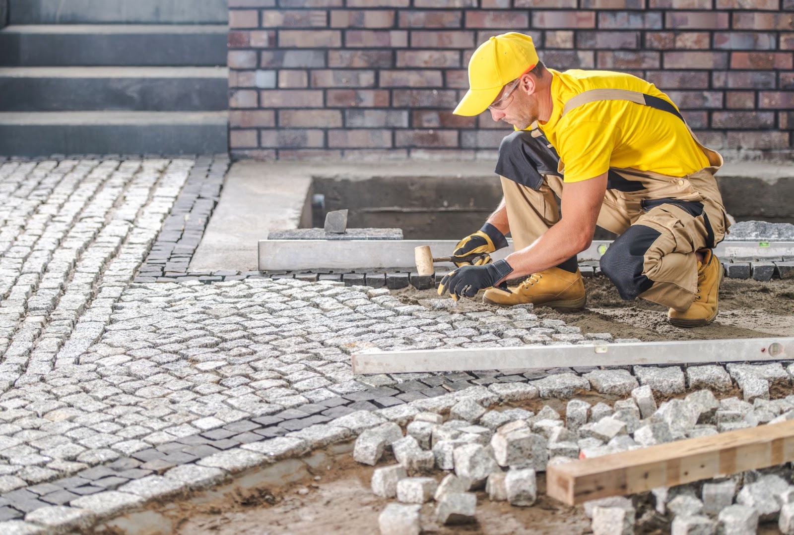 A man is repairing the granite paved hardstanding garden path