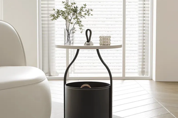 A round side table with a curved leather base with storage, sleek steel supports, and a clean painted top