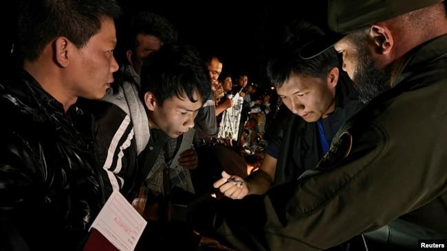 一名中国人正在给一群渡过美墨边境的格兰德河进入美国德克萨斯州的中国人当翻译，向美国边境巡逻人员报到登记，以便进入移民程序。（资料照片：2023年3月23日）