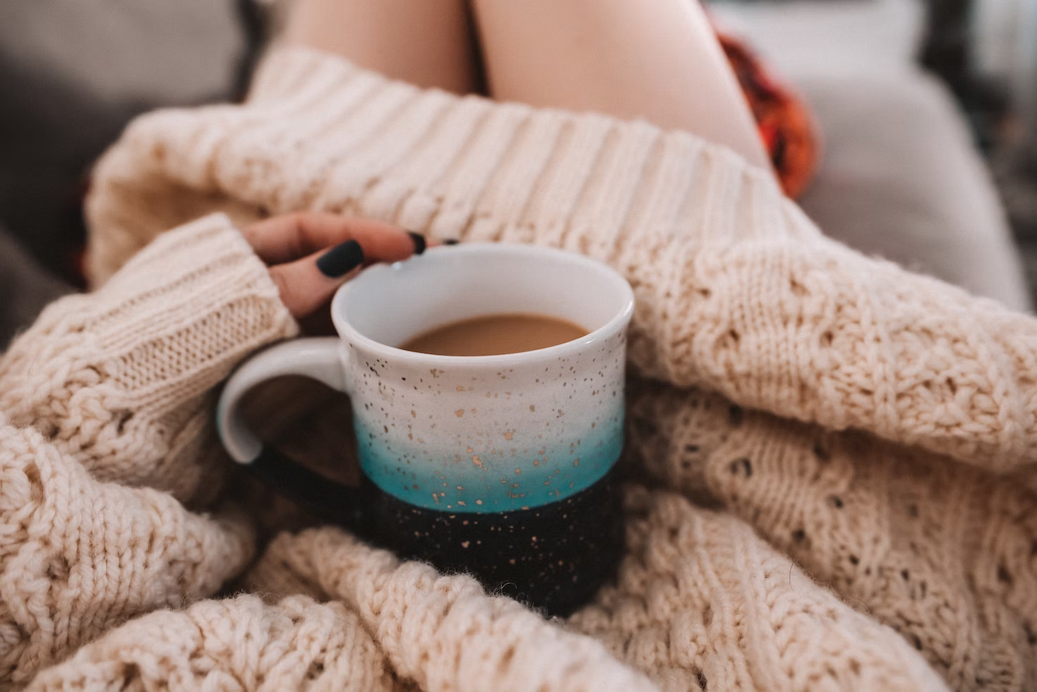Woman in a cozy sweater holding a warm cup of tea