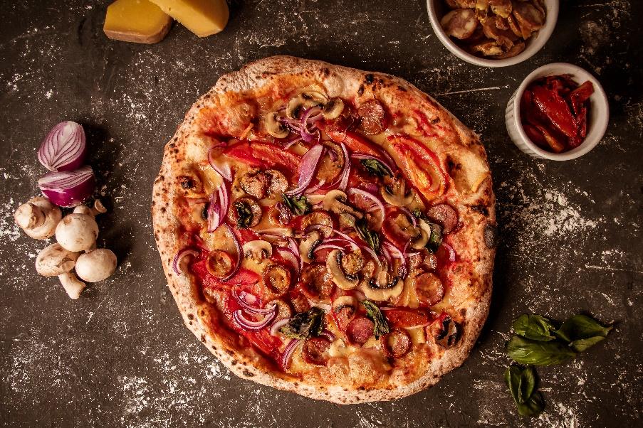 Pizza com massa assada e coberturas diversas    Descrição gerada automaticamente
