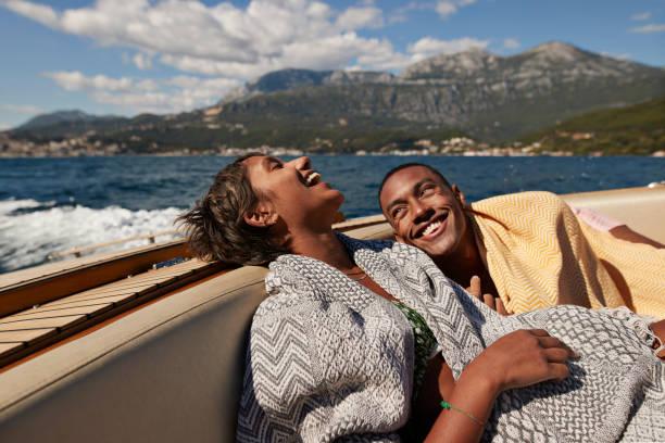 young man and woman laughing in speedboat - black lovers stock pictures, royalty-free photos & images