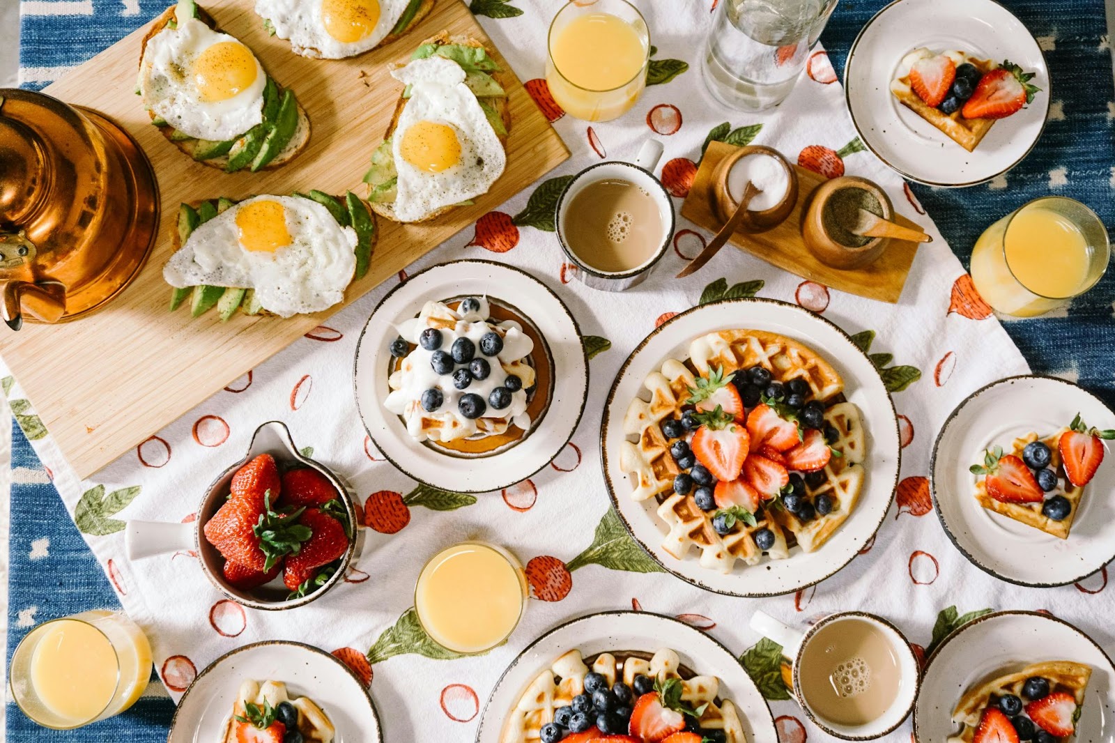a top-down view of breakfast plates and accompaniments on a printed tablecloth