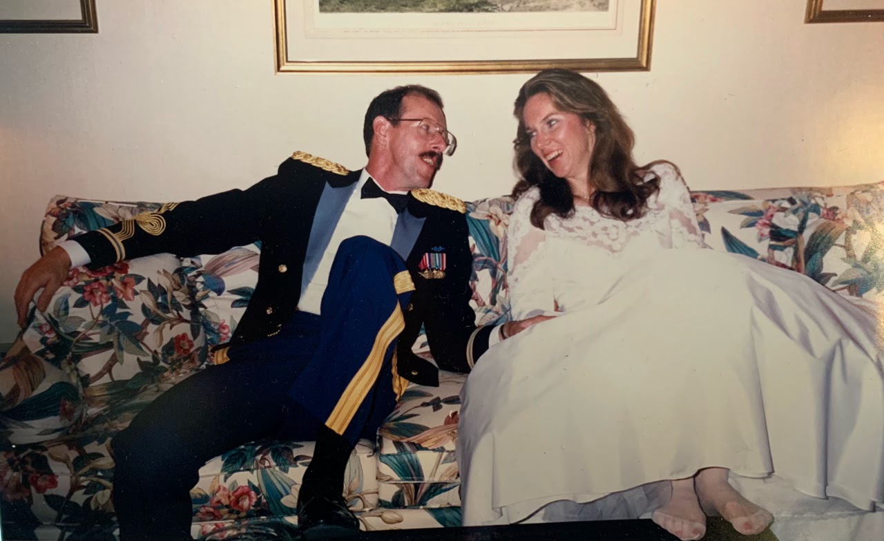 Bonnie and Tom sit on the couch on their wedding day