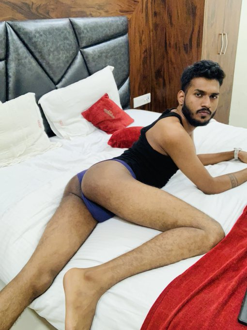 Mr Yuvii  lying on the bed in his blue underwear and black tank top looking back at the camera