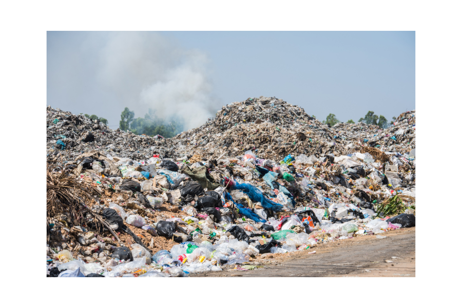 A massive landfill overflowing with discarded clothes of various colours and types.