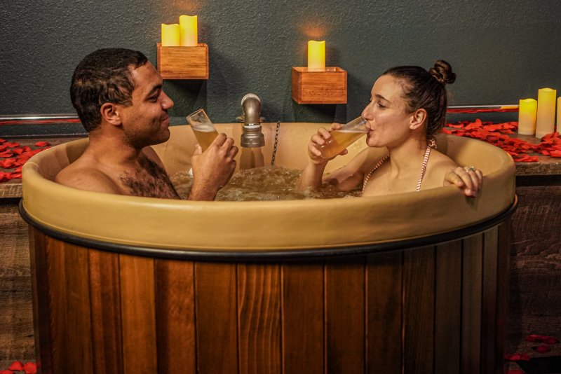 couple sipping champagne and taking a beer bath at Oakwell Beer Spa for a first date in Denver
