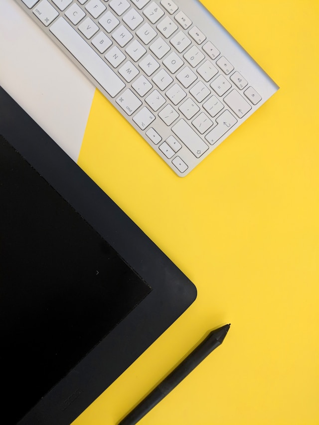 An ipad next to a keyboard used to design prototypes in UI UX on top of a yellow table