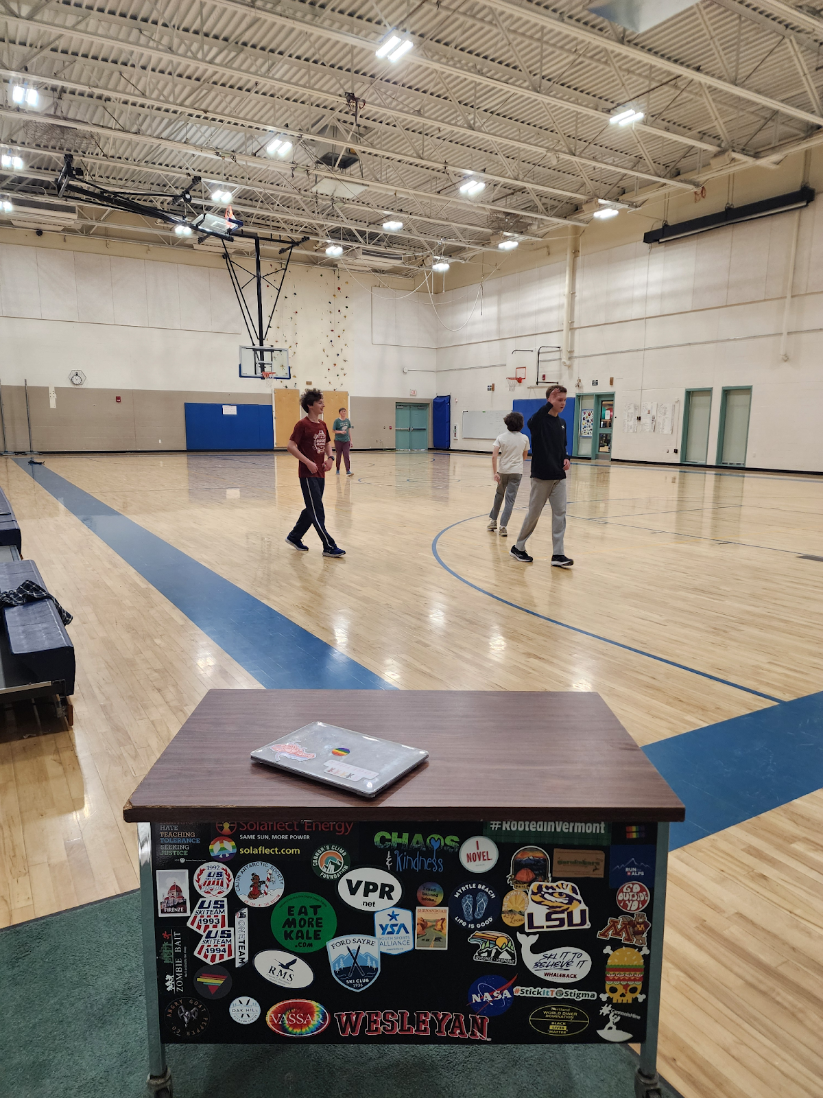 students in the gym, with the rolling desk in the foreground