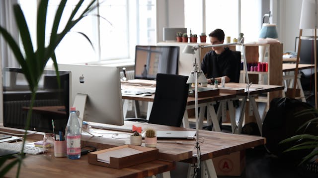 A person working at a desk in an office, focused and busy with his tasks.