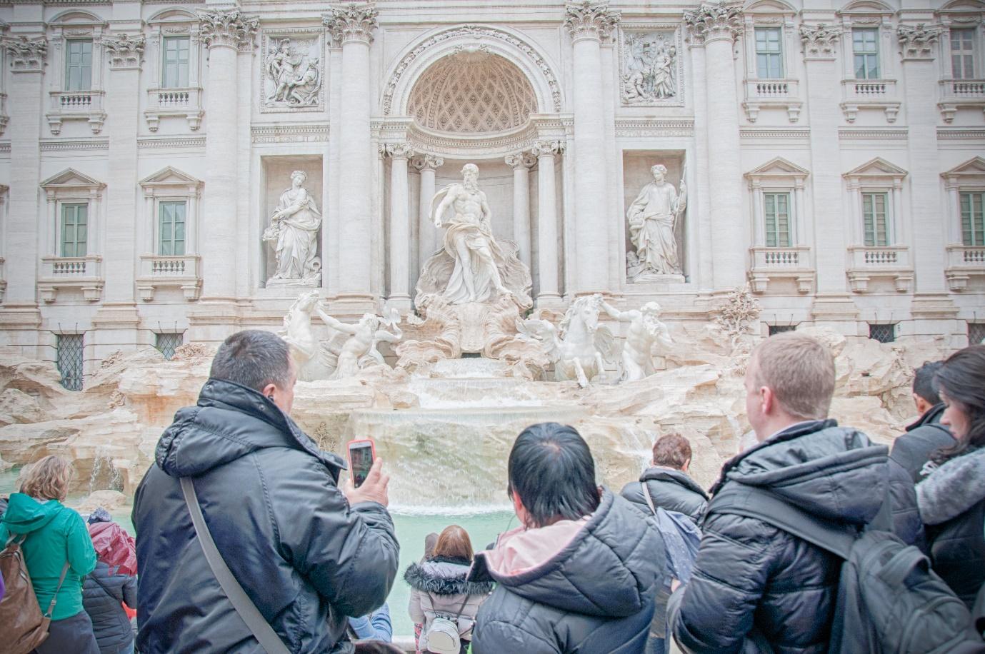 A group of people standing in front of a large white building

Description automatically generated