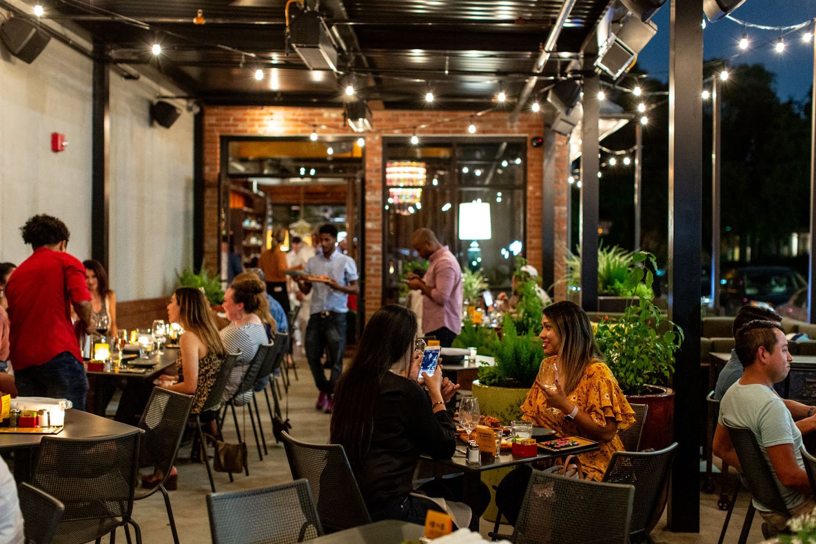 Patio with string lights is filled with diners at Postino