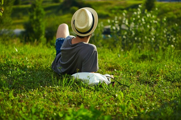 A person wearing a hat and sitting on grass.