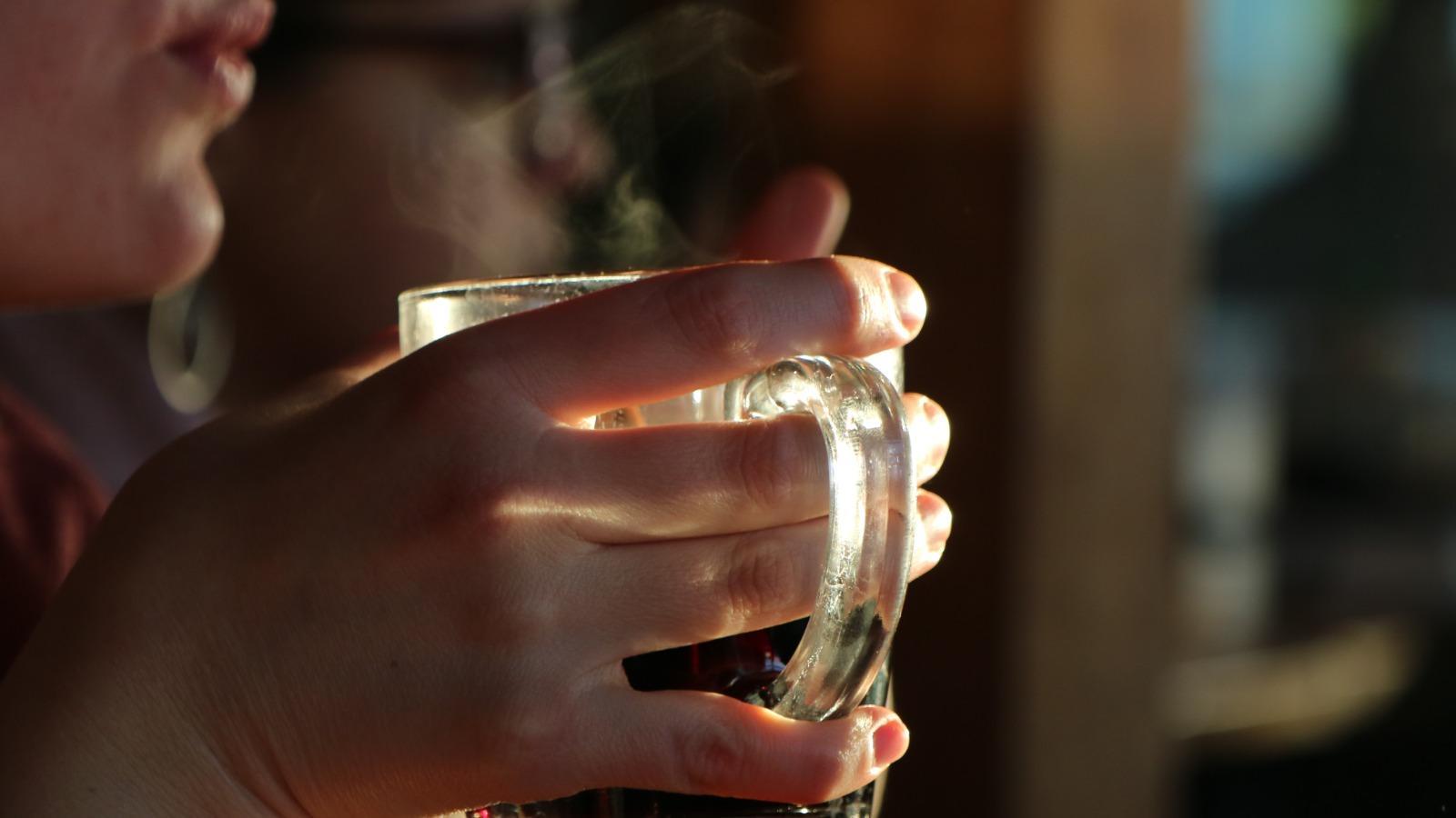 A person holding a glass of liquid

Description automatically generated