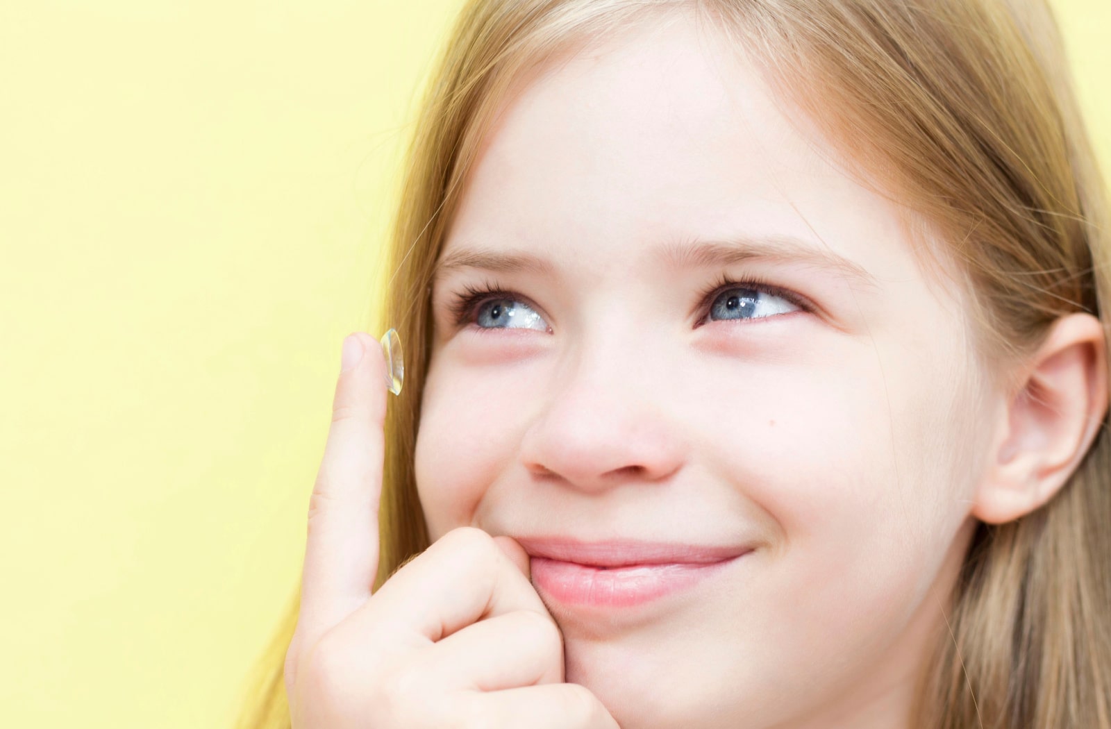 A young girl placing myopia control contact lenses into her eyes