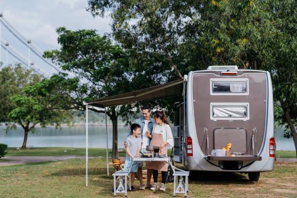 Asian family caravan picnic vacation at public park Image of an Asian Chinese family preparing food together during a caravan picnic vacation at public park car awning stock pictures, royalty-free photos & images