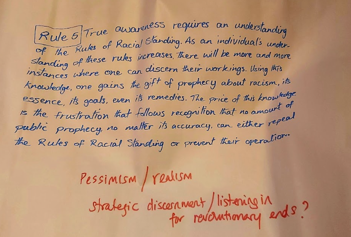 Handwritten text on filpchart paper: Rule 5: True awareness requires an understanding of the Rules of Racial Standing. As an individuals understanding of these rules increases, there will be more and more instances where one can discern their workings. Using this knowledge, one gains the gift of prophesy about racism, its essence, its goals, even its remedies. The price of this knowledge is the frustration that follows recognition that no amount of public prophecy, no matter its accuracy, can either repeal the Rules of Racial Standing nor prevent their operation.
(Notes underneath this read:  pessimism/realism
strategic discernment / listening in for revolutionary ends?