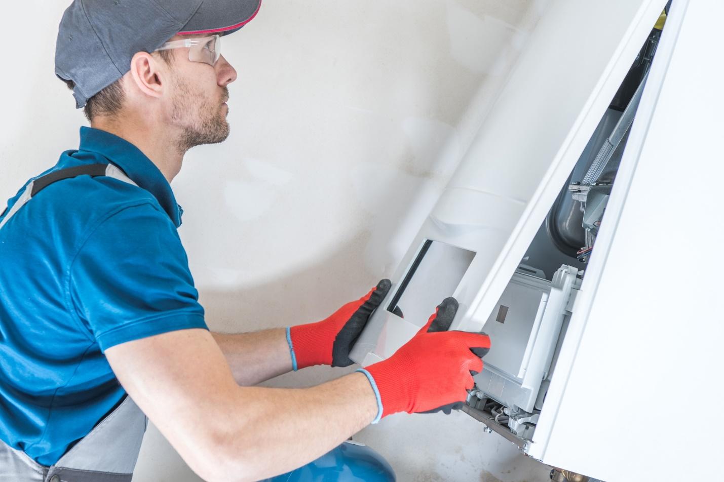 A person in a blue shirt and red gloves working on a white machine