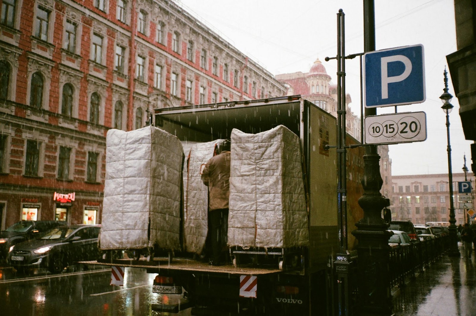 A box truck with its back hatch open on a rainy day